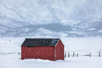 House on snow field against sky