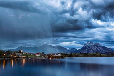 Scenic view of lake by mountain against dramatic sky