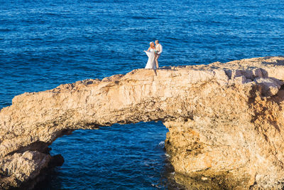 Man standing on rock by sea