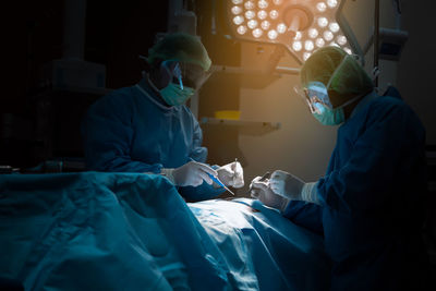 Surgeons operating patient in room
