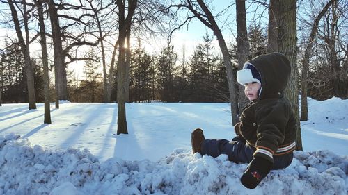 Baby boy sitting on snow covered field