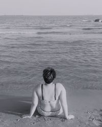 Rear view of woman sitting on beach