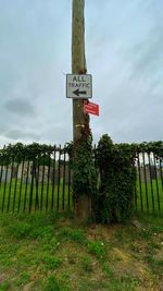 Information sign on field against sky