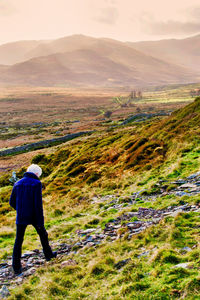 Rear view of man looking at mountains against sky