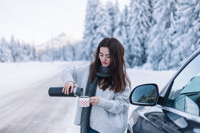 Portrait of young woman sitting on car