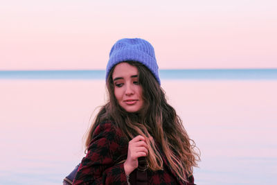 Portrait of beautiful young woman against sea during sunset