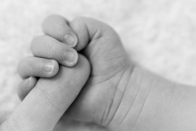 Close-up of baby hands holding parent finger
