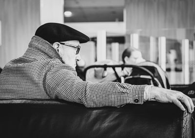 Side view of young man sitting on table at home