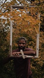 Full length of young man standing by tree in forest