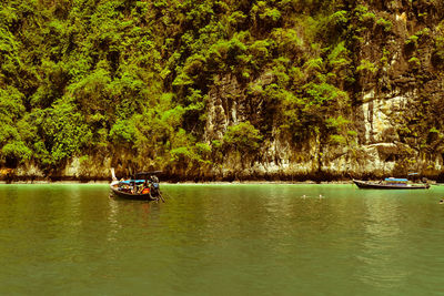 Boat sailing on river amidst trees in forest