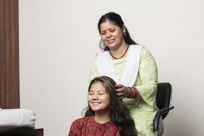 Portrait of a smiling young woman sitting against wall