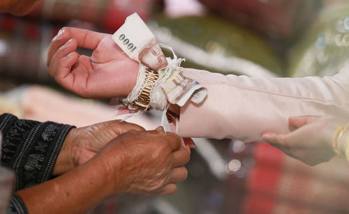 Cropped hands of woman performing rituals with bride and groom during wedding