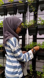 Side view of woman standing against plants