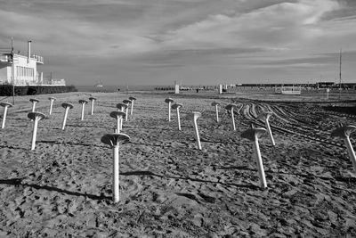 Wooden posts on beach against sky