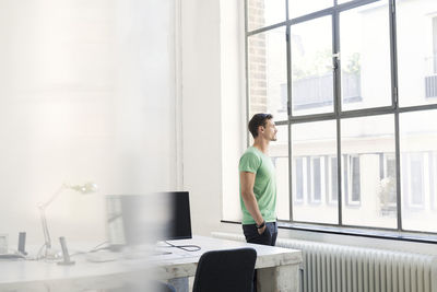 Young businessman looking out of office window, looking pensive