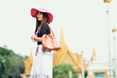 Portrait of young woman wearing hat against clear sky