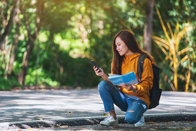 Young woman using mobile phone while sitting outdoors