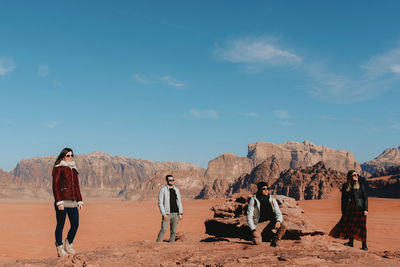 Rear view of people standing on rock against sky