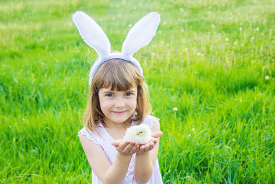 Portrait of woman with rabbit on grassy field