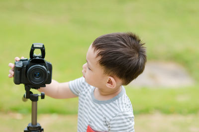 Cute boy photographing while standing at park