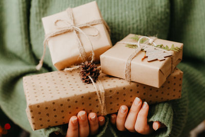 Closeup of woman in green pullover holding many gift boxes in her hands. close up.