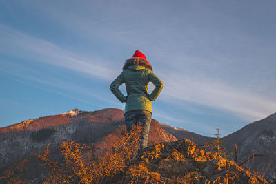 Rear view of man standing on mountain against sky