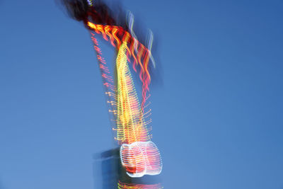 Low angle view of illuminated lanterns against clear blue sky