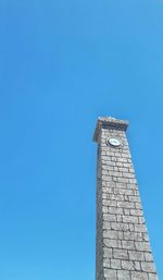 Low angle view of clock tower against blue sky