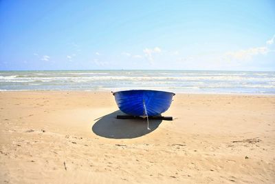 Deck chairs on beach against blue sky