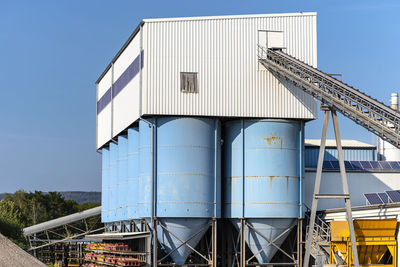 Big blue metallic industrial silos for the production of cement at an industrial cement plant.