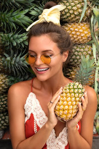 Portrait of young woman holding pineapple