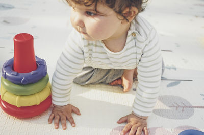 Cute boy playing with toy sitting on floor