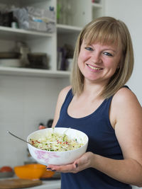 Smiling young woman with salad at home