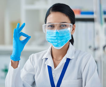 Female scientist wearing mask standing in laboratory