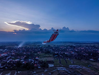 Airplane flying over cityscape against sky