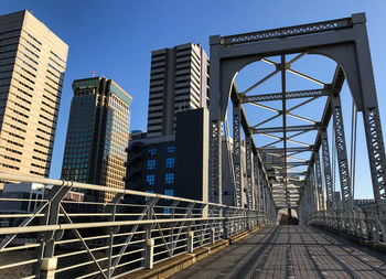 Low angle view of bridge and buildings against clear blue sky