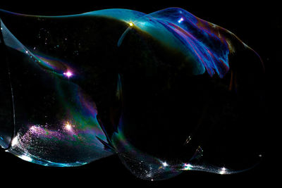 Close-up of bubbles over water against black background