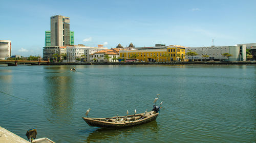 Boat in river by city against sky