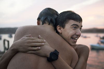 Cheerful wet brothers embracing at beach