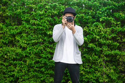 Man wearing hat standing against plants