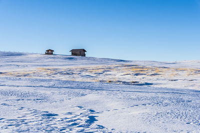 Scenic view of snowcapped field against clear blue sky