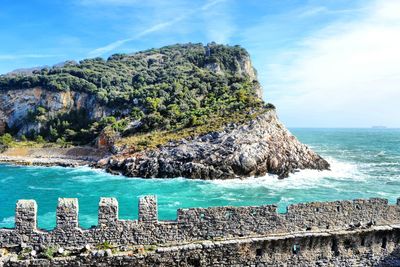 Scenic view of rocks on sea shore against sky