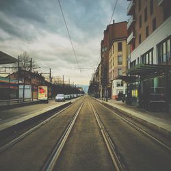 Railroad tracks against cloudy sky