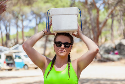 Portrait of woman carrying box at forest