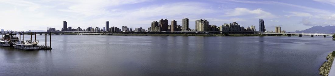 Panoramic view of bay and buildings against sky