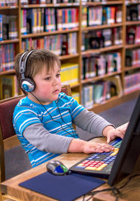 Portrait of boy using laptop at library