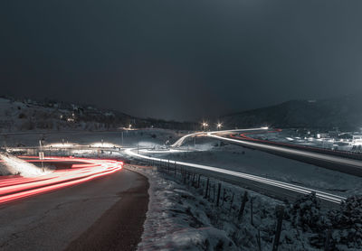 Light trails on street against clear sky at night during winter