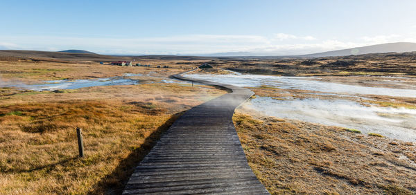 Walkway amidst landscape against sky