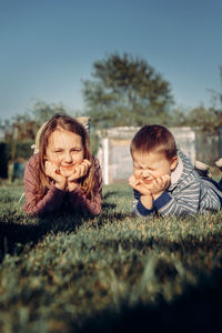 Side view of siblings on field against sky