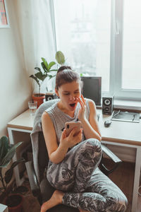 High angle view of woman using smart phone while sitting at home